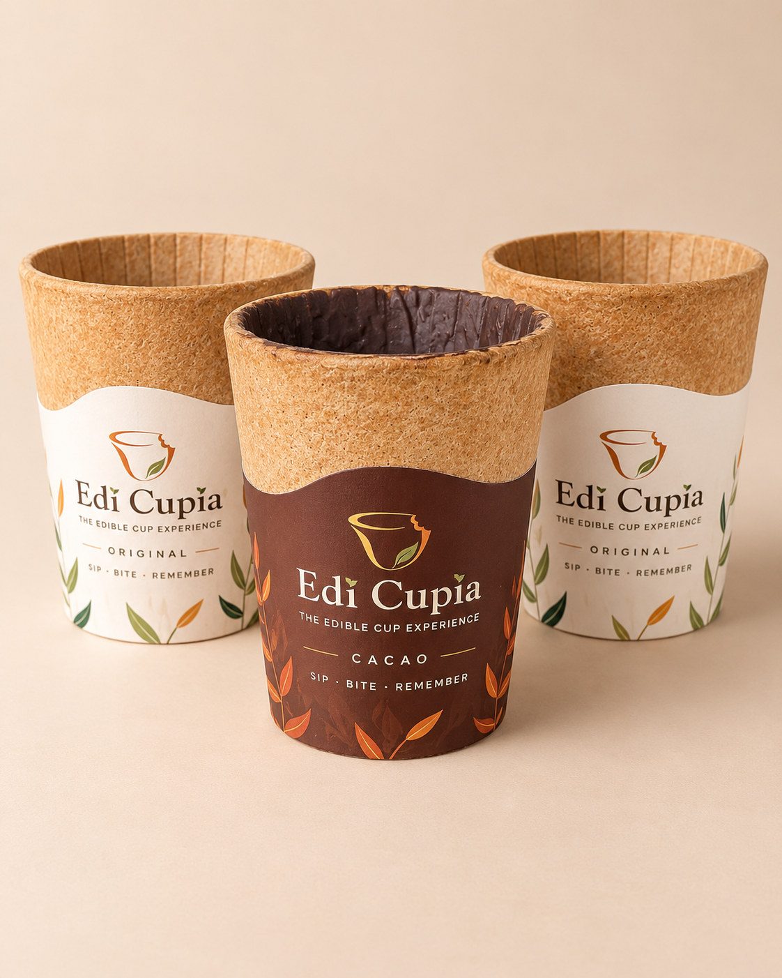 Trois tasses comestibles en gaufrette Edi Cupia, une tasse Cacao tapissée de chocolat devant deux tasses Original aux manchons ivoire.