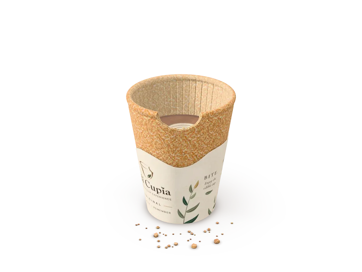 Une tasse Edi Cupia remplie d’un latte, croquée sur le bord, avec quelques miettes à côté.